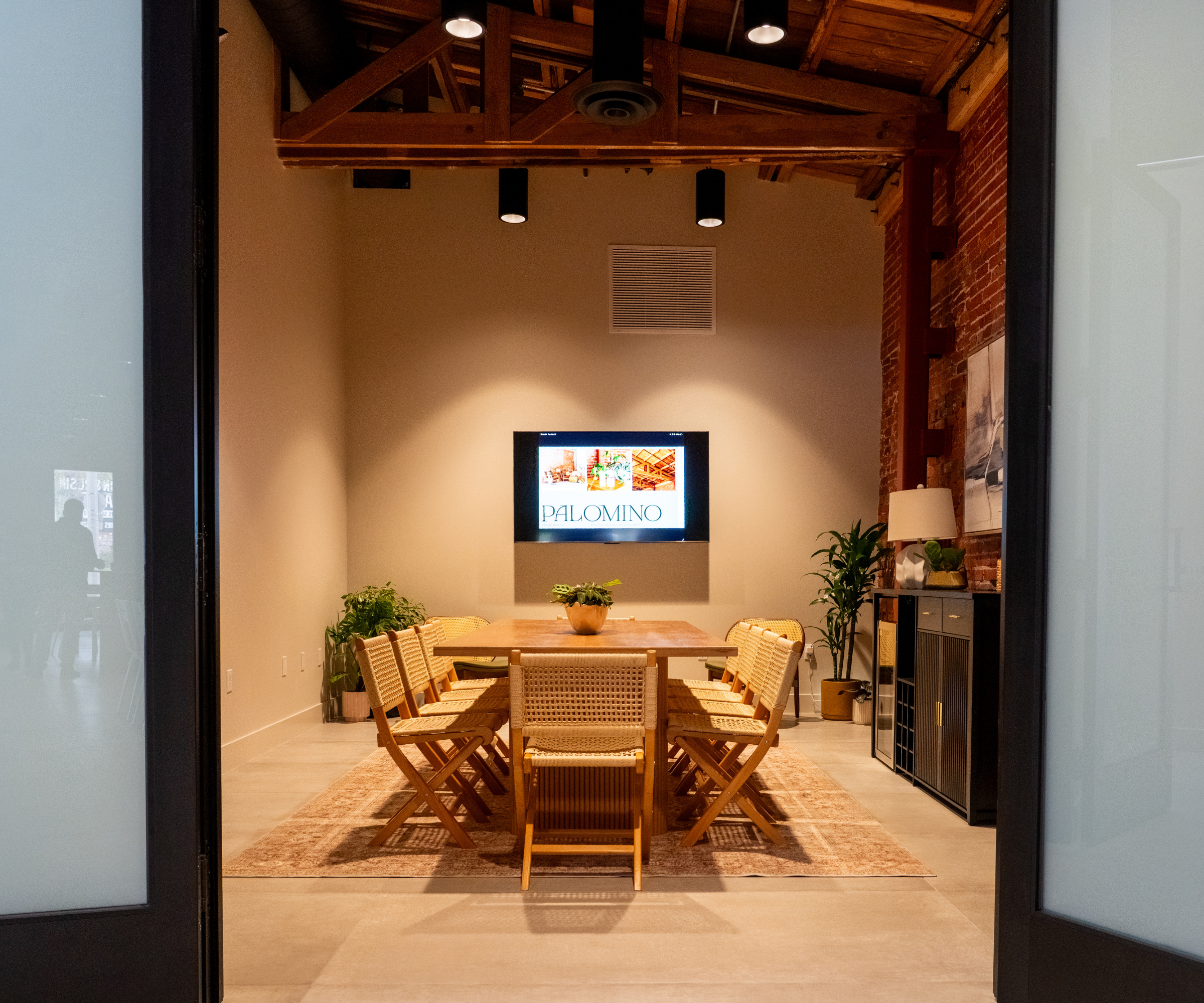 Wood conference table and cane chairs arranged beneath exposed beams in Palomino’s private meeting room.