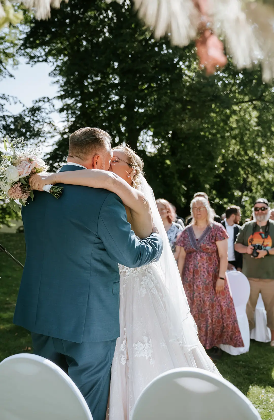 Bräutigam hebt die Braut im Park, sie streckt den Brautstrauß hoch – Berlin; natürliche Hochzeitsfotografie, emotionale Hochzeitsbilder