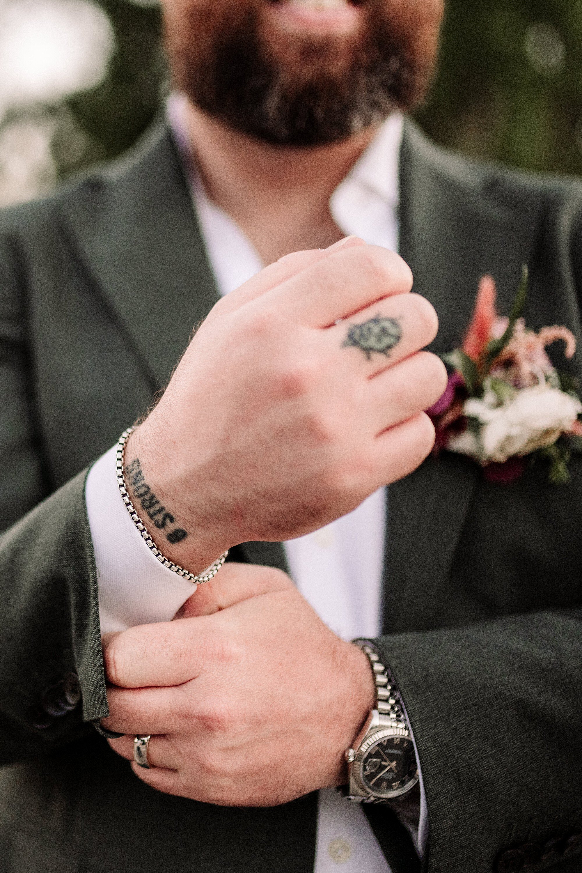 Close up of a groom adjusting his boutonniere