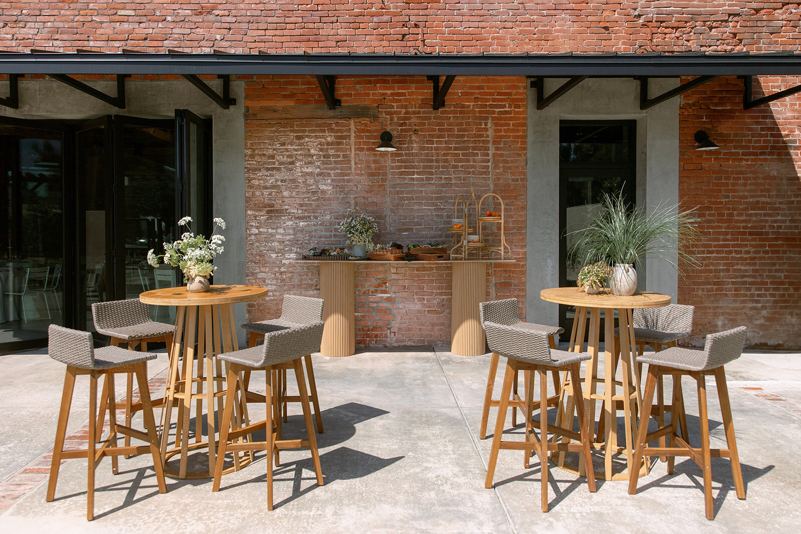 Wood cocktail tables and woven stools arranged outside Palomino’s open sliding doors.