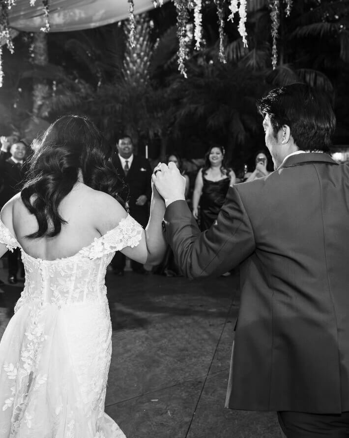 Newlyweds dancing with guests at their reception in black and white