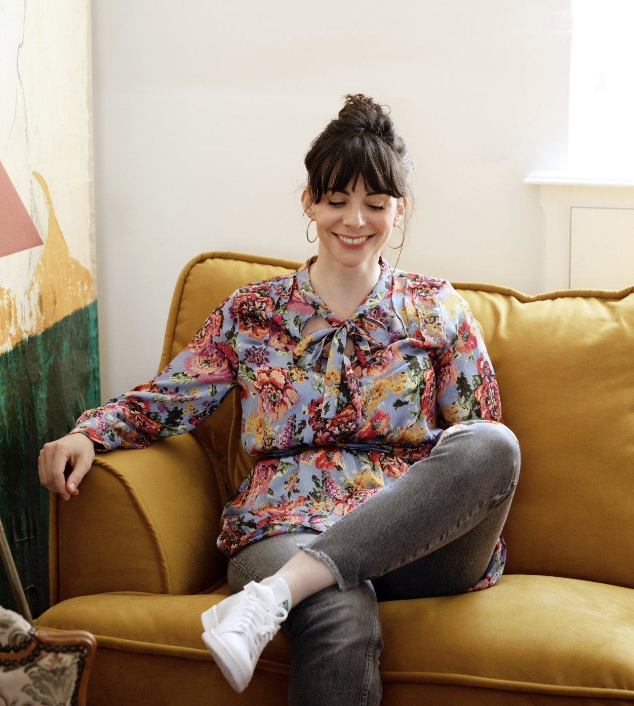 Maud Simon, souriante, assise sur un canapé jaune