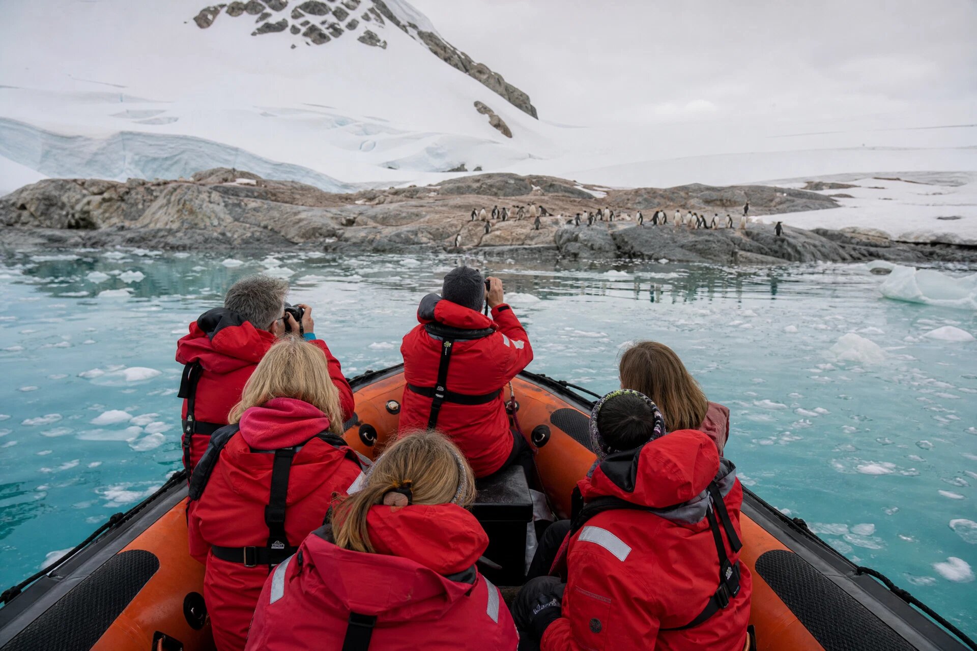 Zodiac boat approaching Antarctic shore with penguins