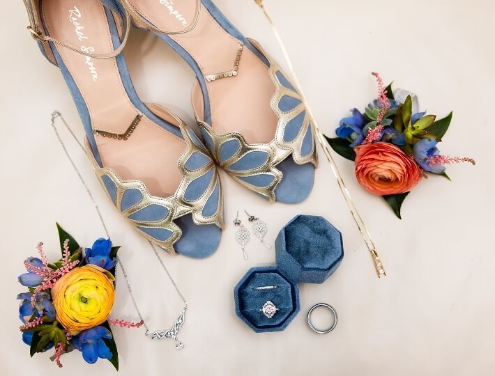 Blue bridal shoes, wedding rings, jewelry and colorful boutonnieres