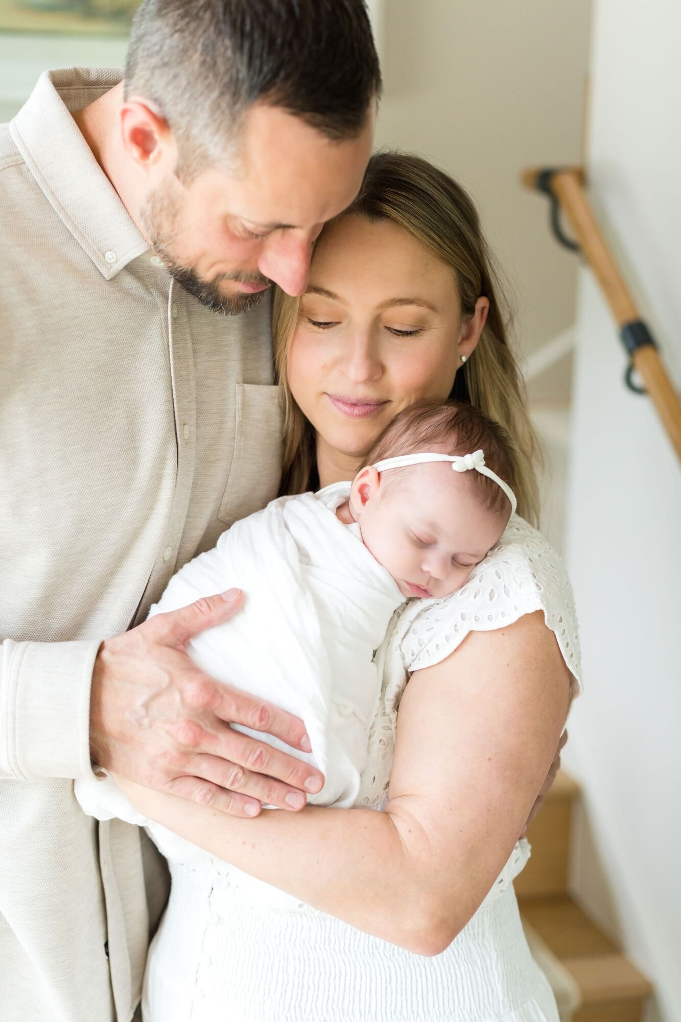 Mom and dad holding their sleeping newborn close at home in Austin