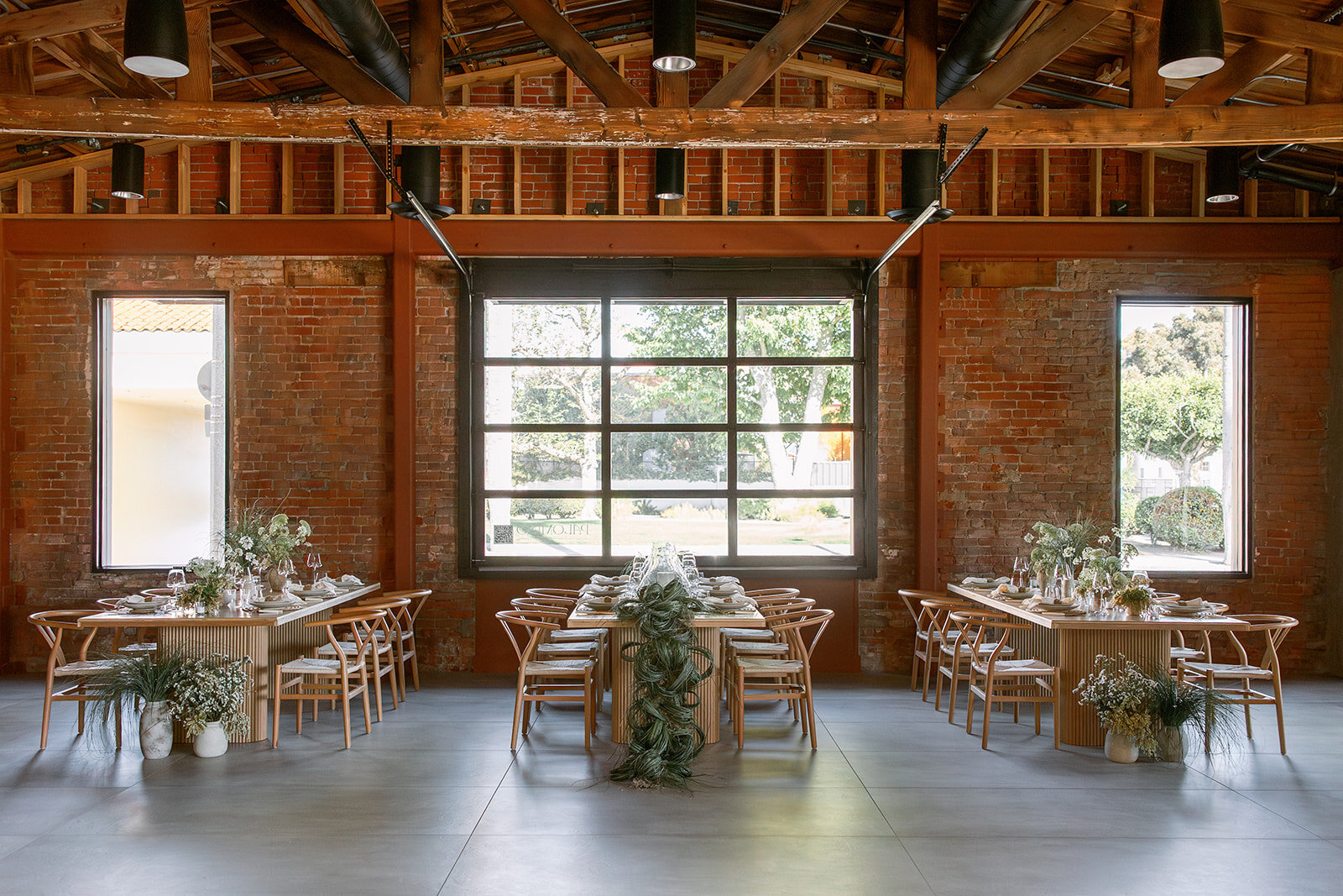 Three wood dining tables arranged beneath exposed beams and against Palomino’s original brick walls.