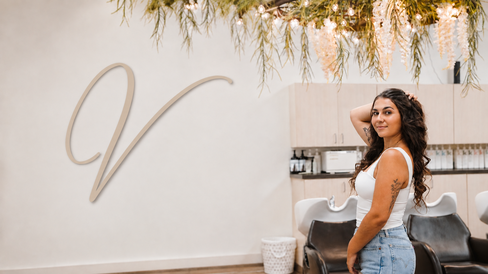 Vogue Salon & Med Spa interior with a taupe V monogram and a guest beside the shampoo stations