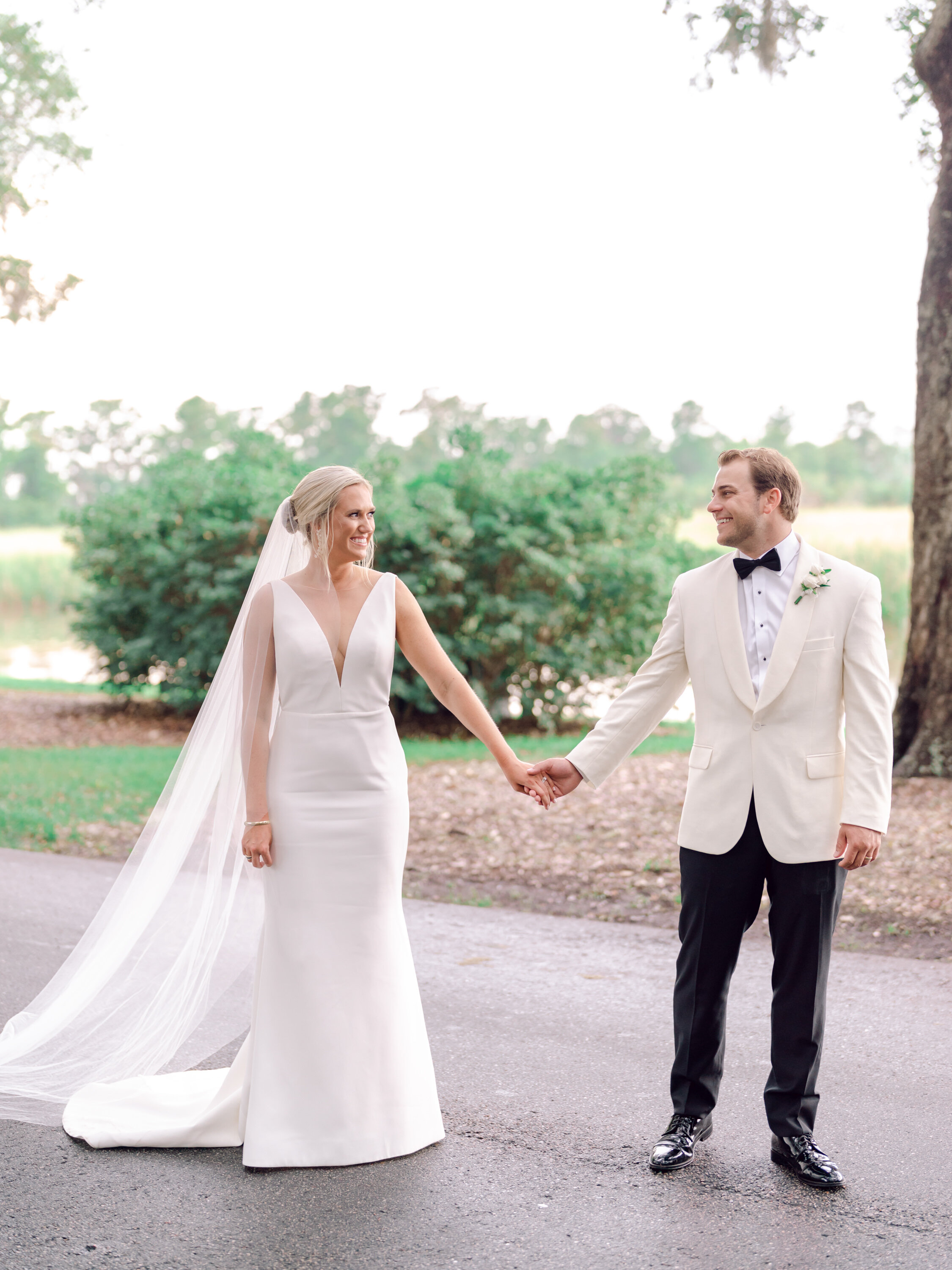Bride and groom walking beneath live oak trees at Caledonia Golf and Fish Club in Pawleys Island, SC
