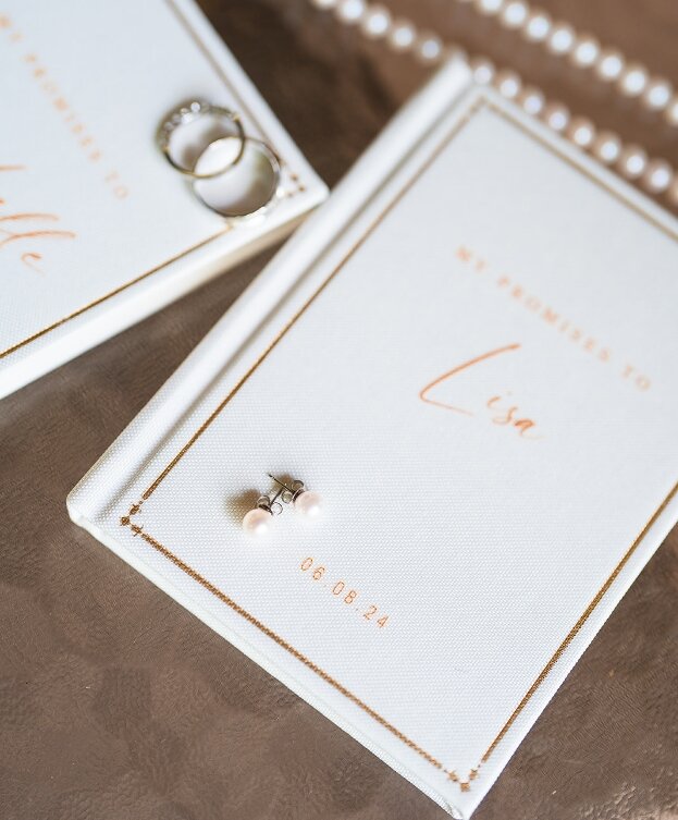 Personalized wedding vow books with rings and pearl earrings