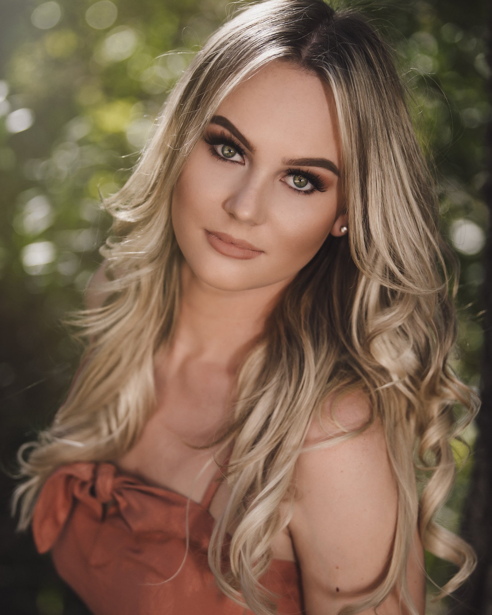 Close-up senior portrait of a blonde high school senior with long curls, by senior photographer Renee Bowen