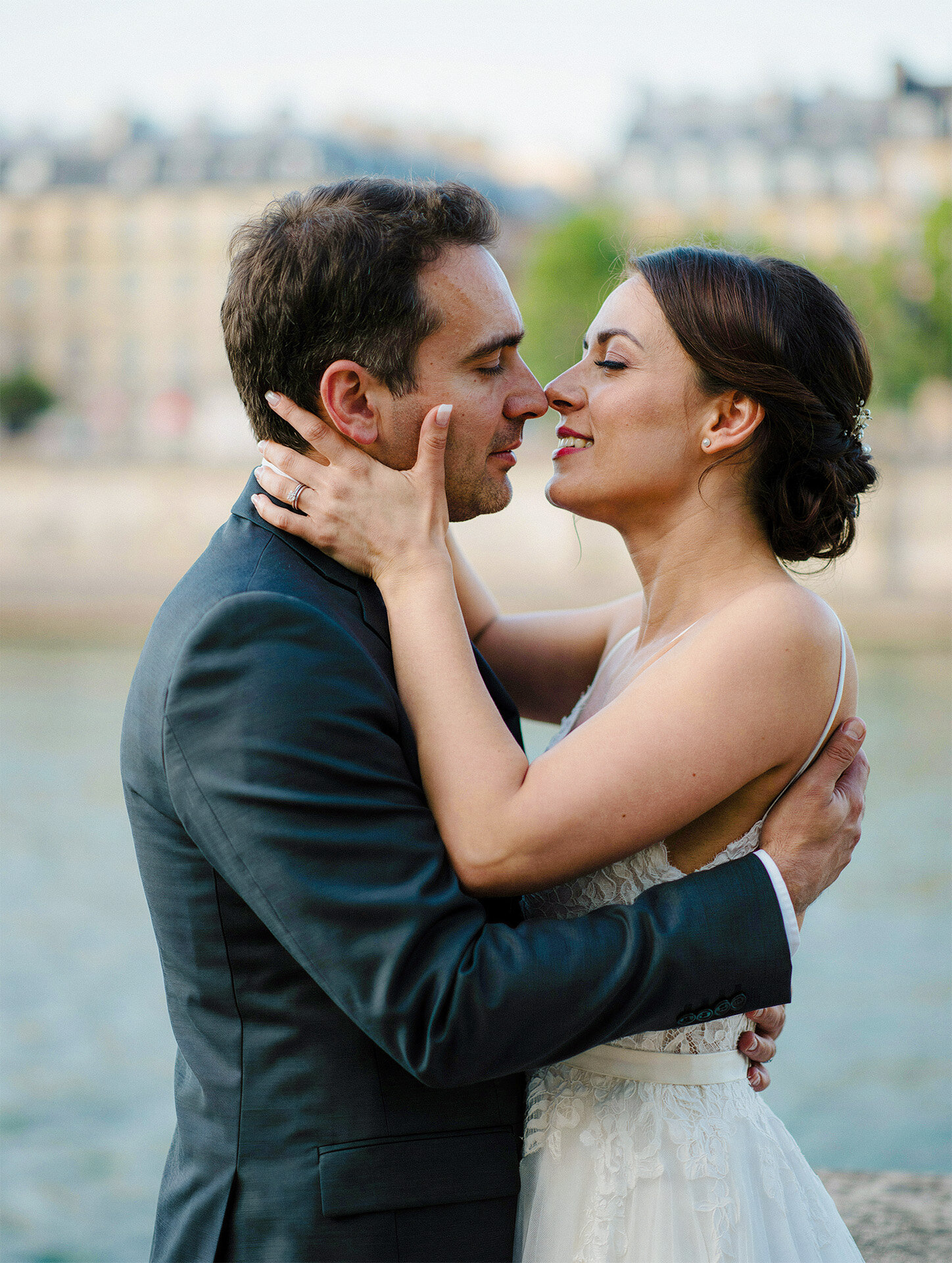 Bride and groom embracing beside the Seine River in Paris, France