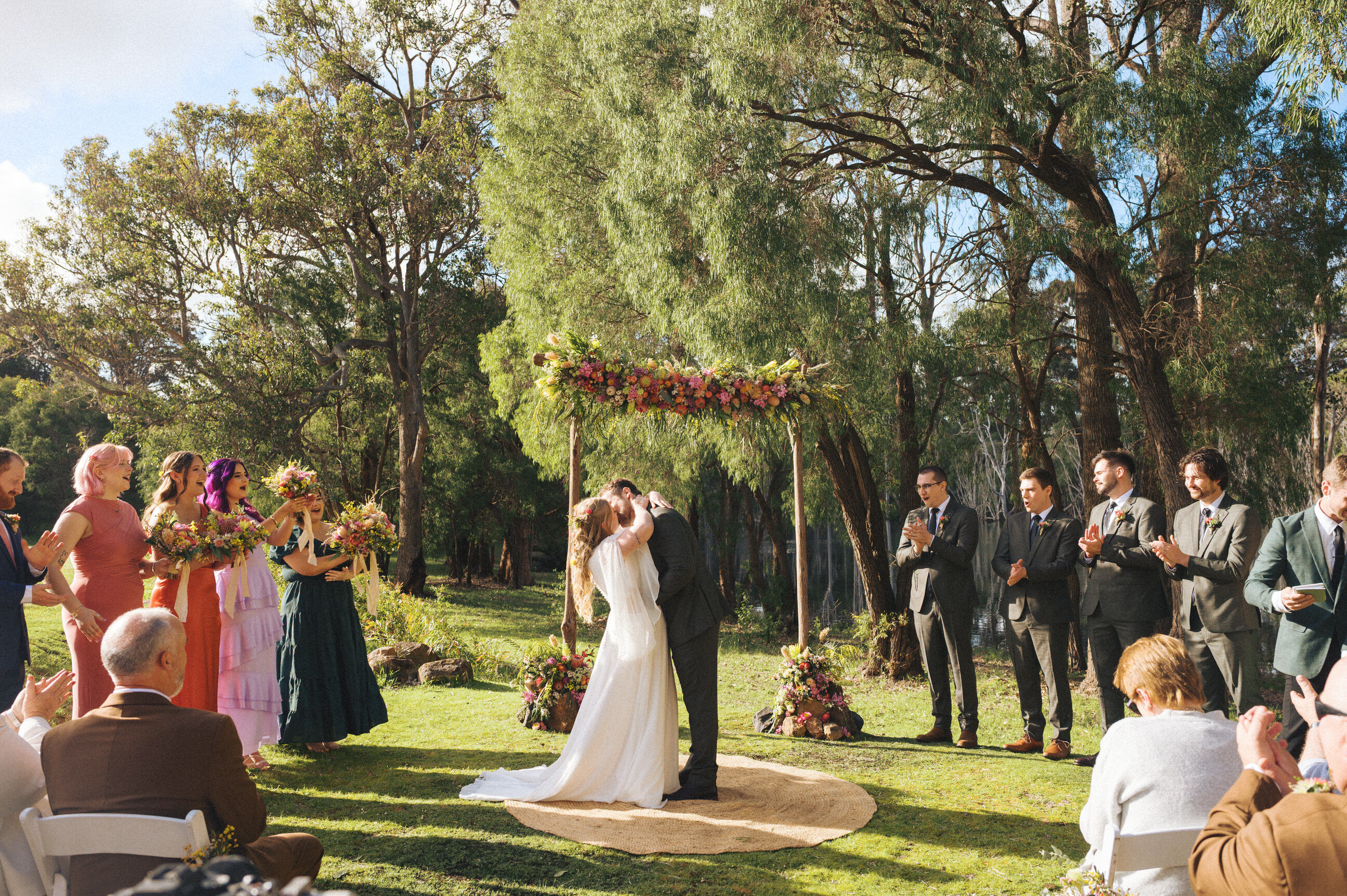 A couple sharing their first kiss during a forest wedding ceremony at Harmony Forest near Margaret River