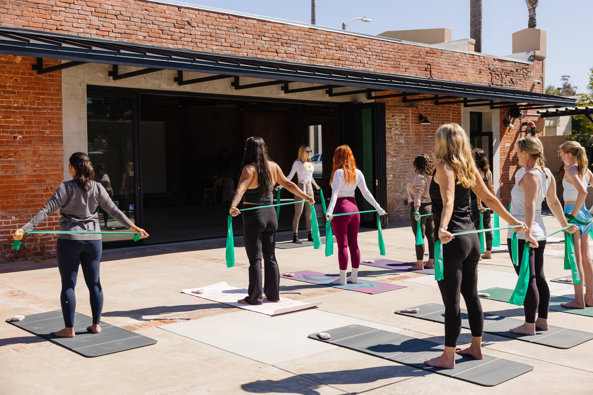 Guests using resistance bands during an outdoor wellness class beside Palomino’s open interior.