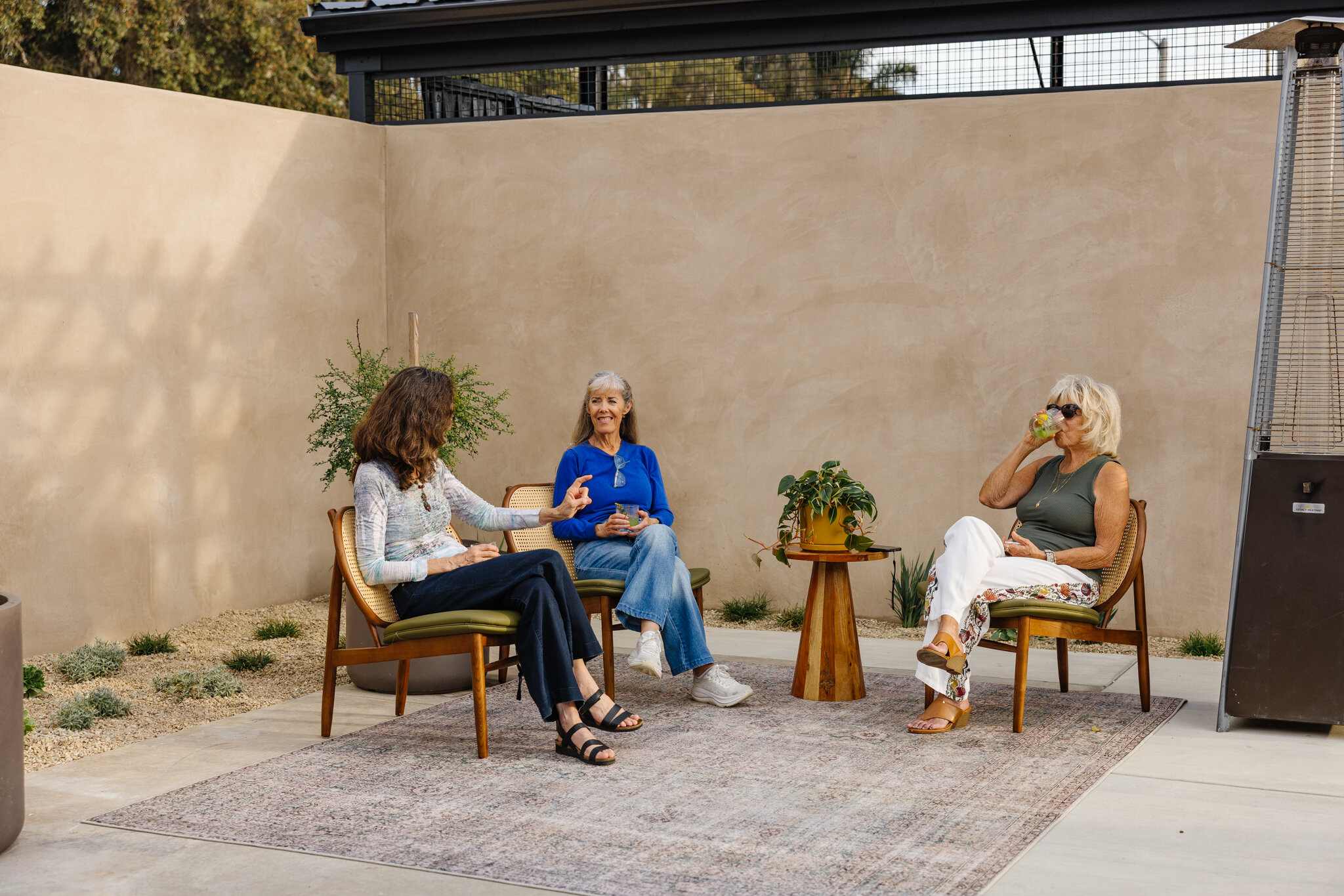 Three guests talking over drinks in an intimate seating area on Palomino’s patio.