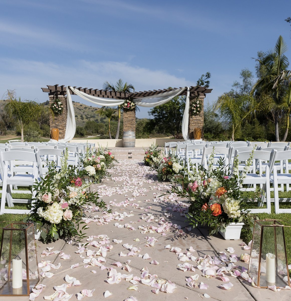 Romantic wedding ceremony aisle with floral arrangements and soft petals.