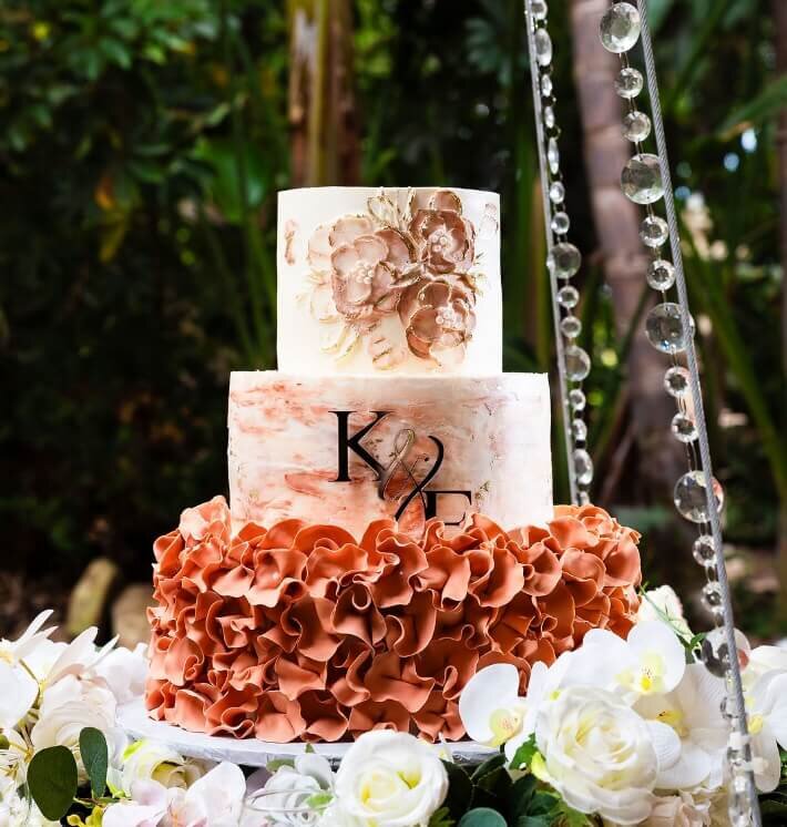 Three-tier wedding cake decorated with peach florals and white flowers