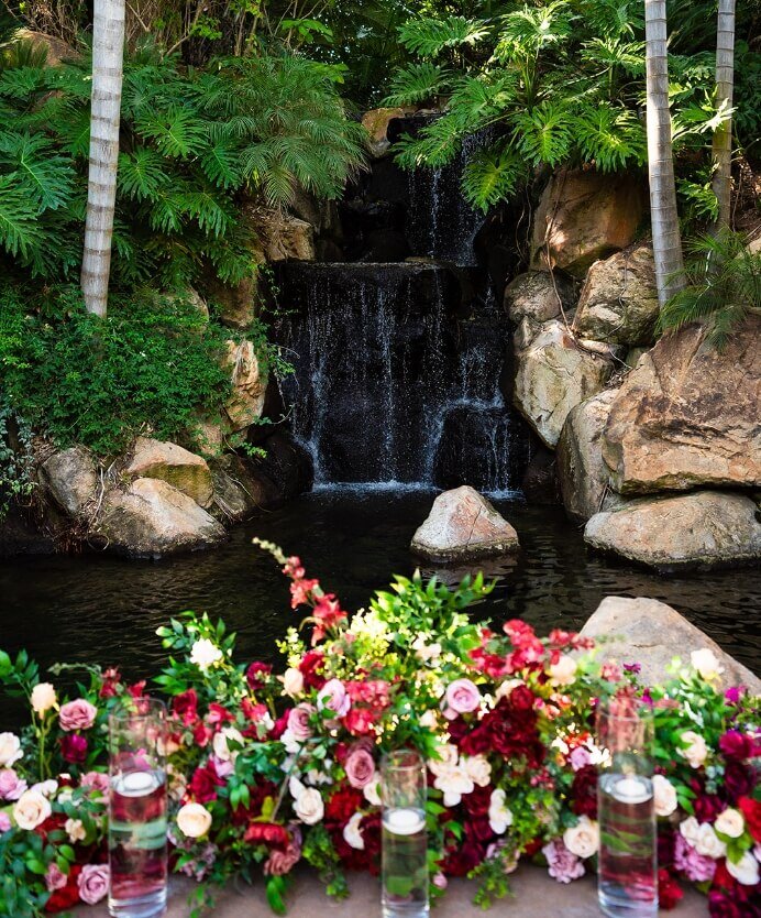 Colorful SoCal wedding florals arranged beside a garden waterfall