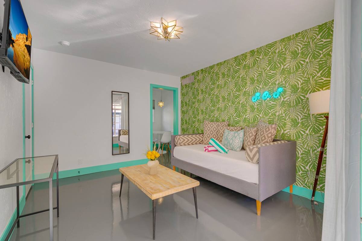Sitting room with neon sign and monstera wallpaper