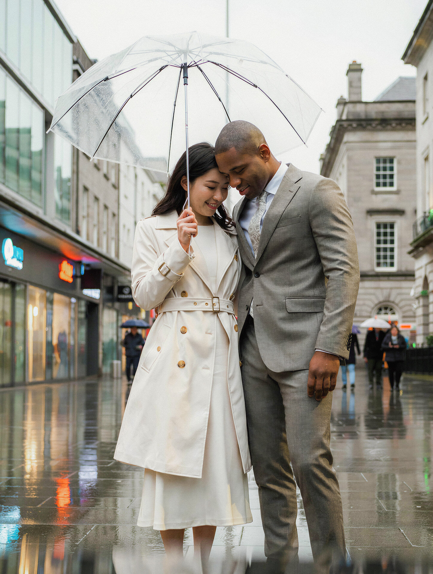 Bride and groom with an umbrella on a rainy Irish street photographed by an Ireland destination wedding photographer