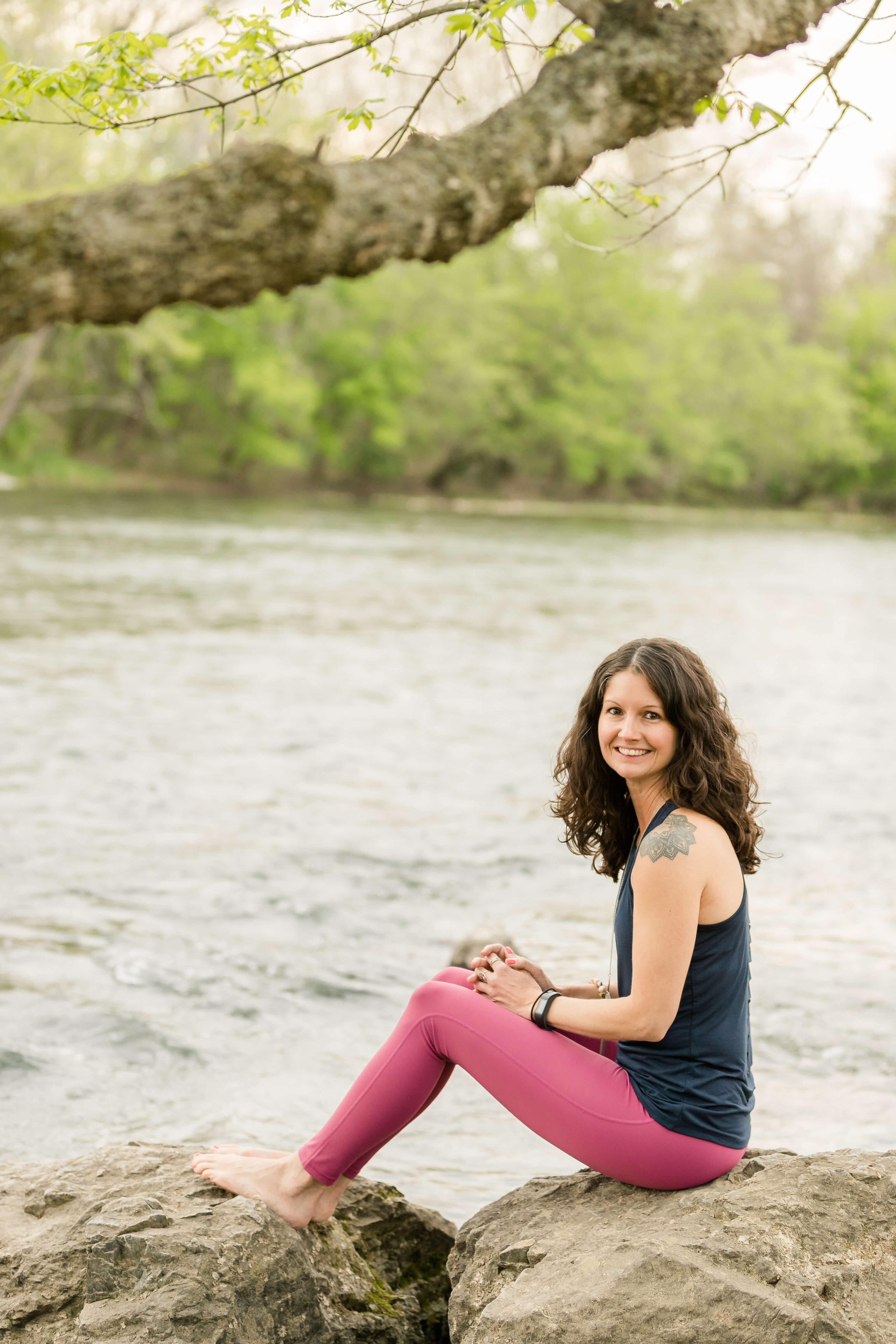 Rachel Cline sitting on a rock beside a river