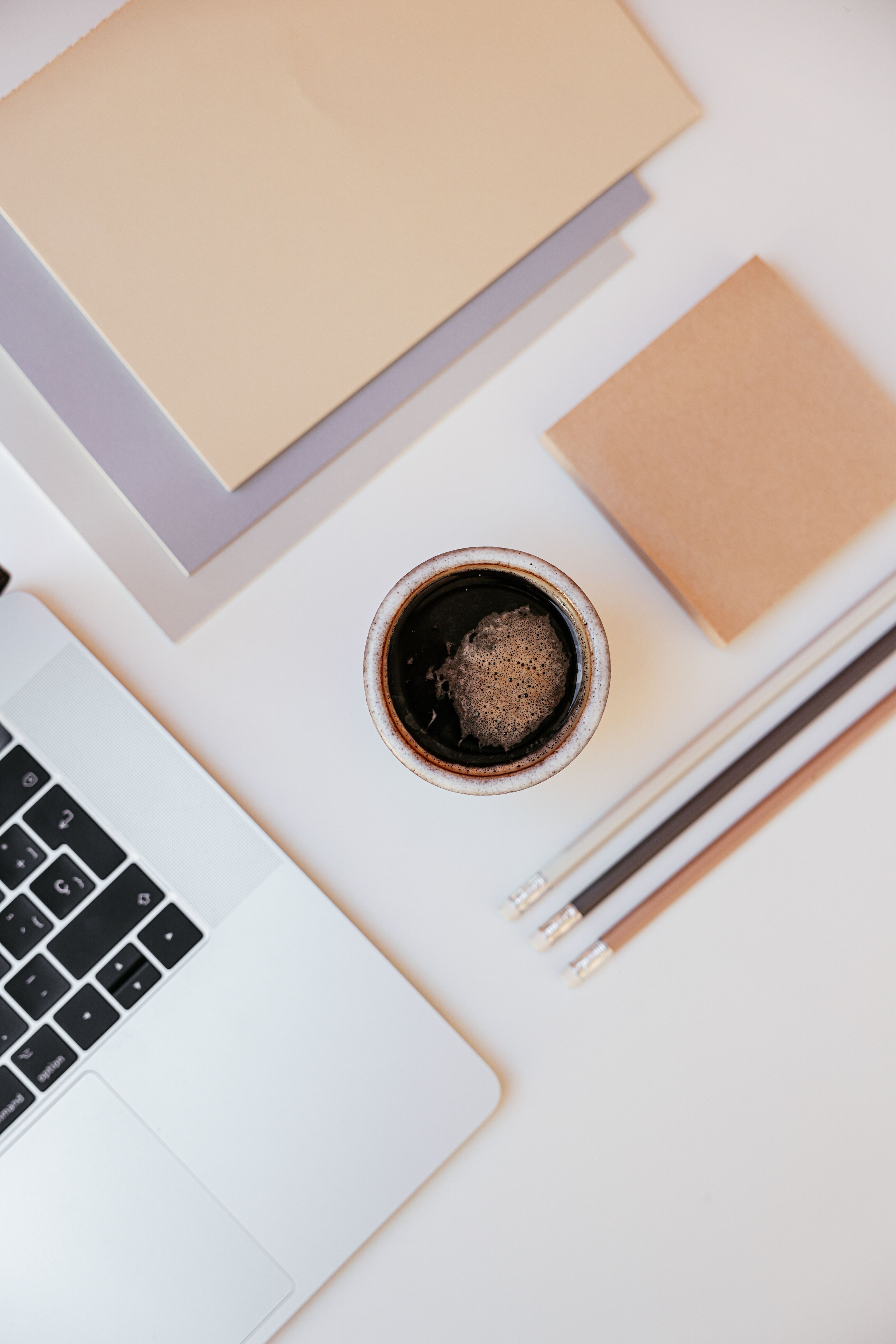 Desk flatlay with laptop, coffee and notebooks