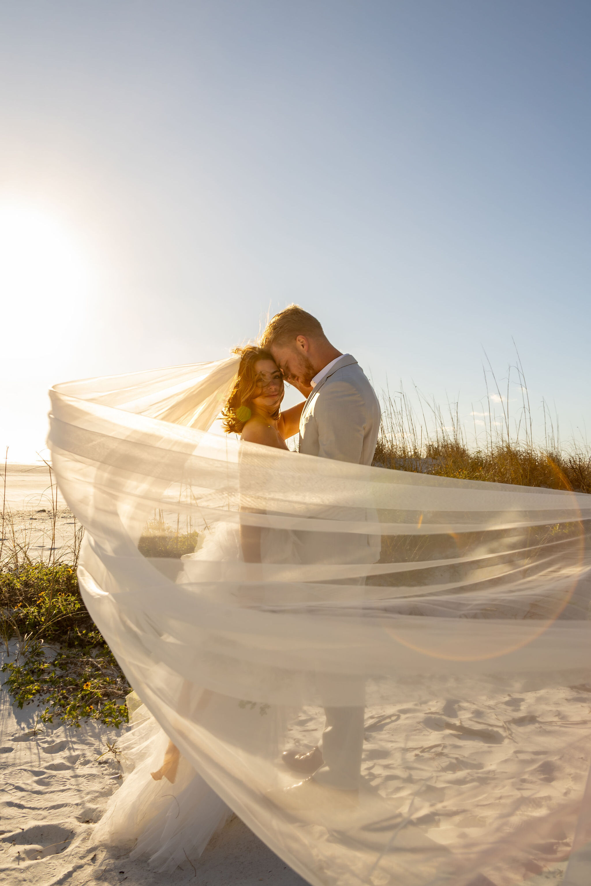 Couple eloping on the beach bride with stunning veil