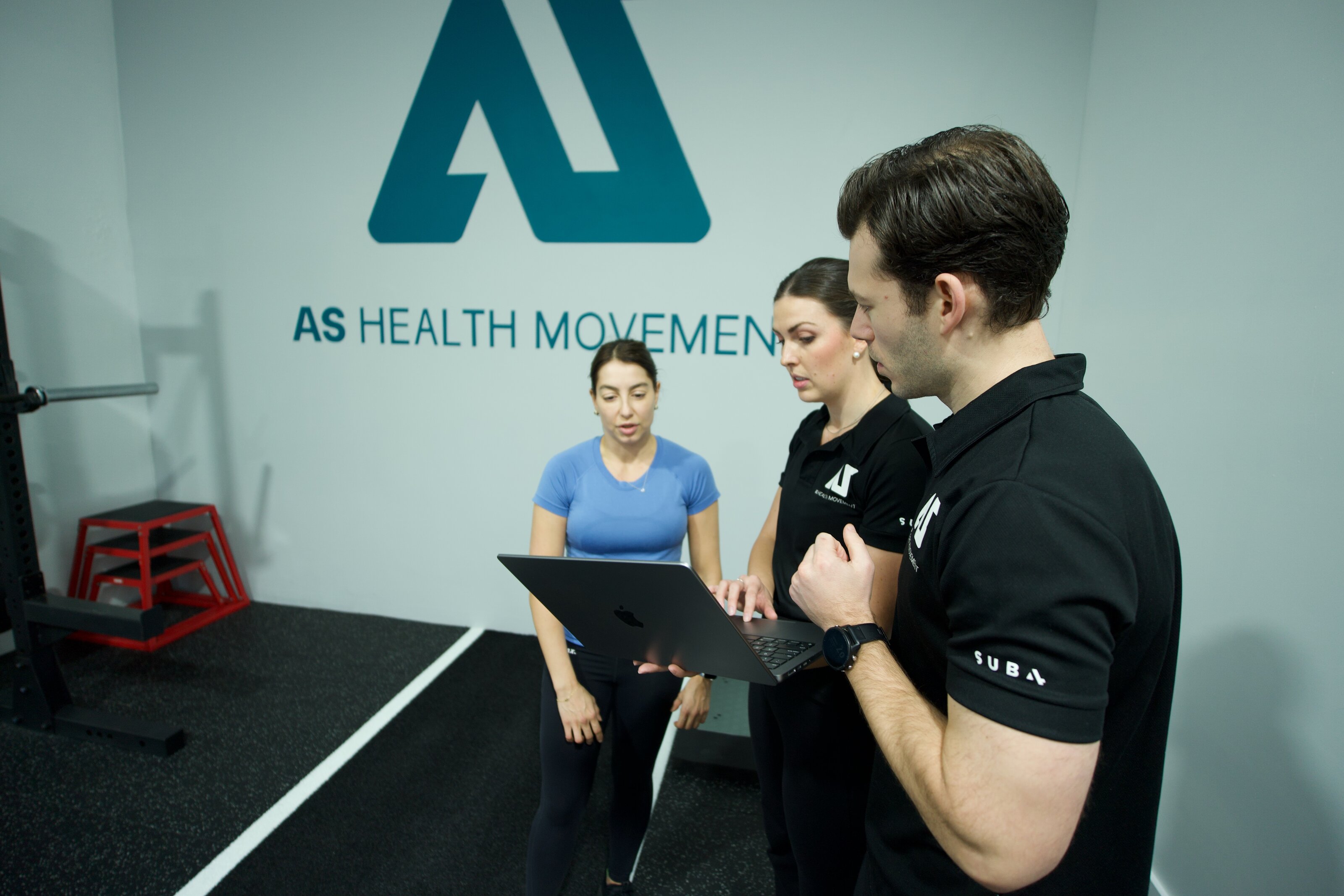 AS Health Movement client session in front of the logo wall