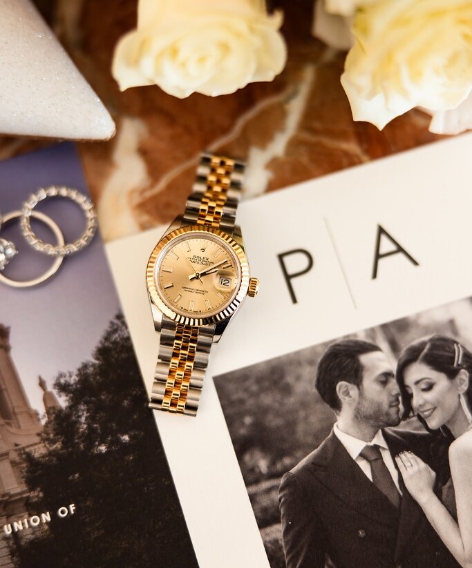 Wedding rings, watch and printed couple portrait arranged together