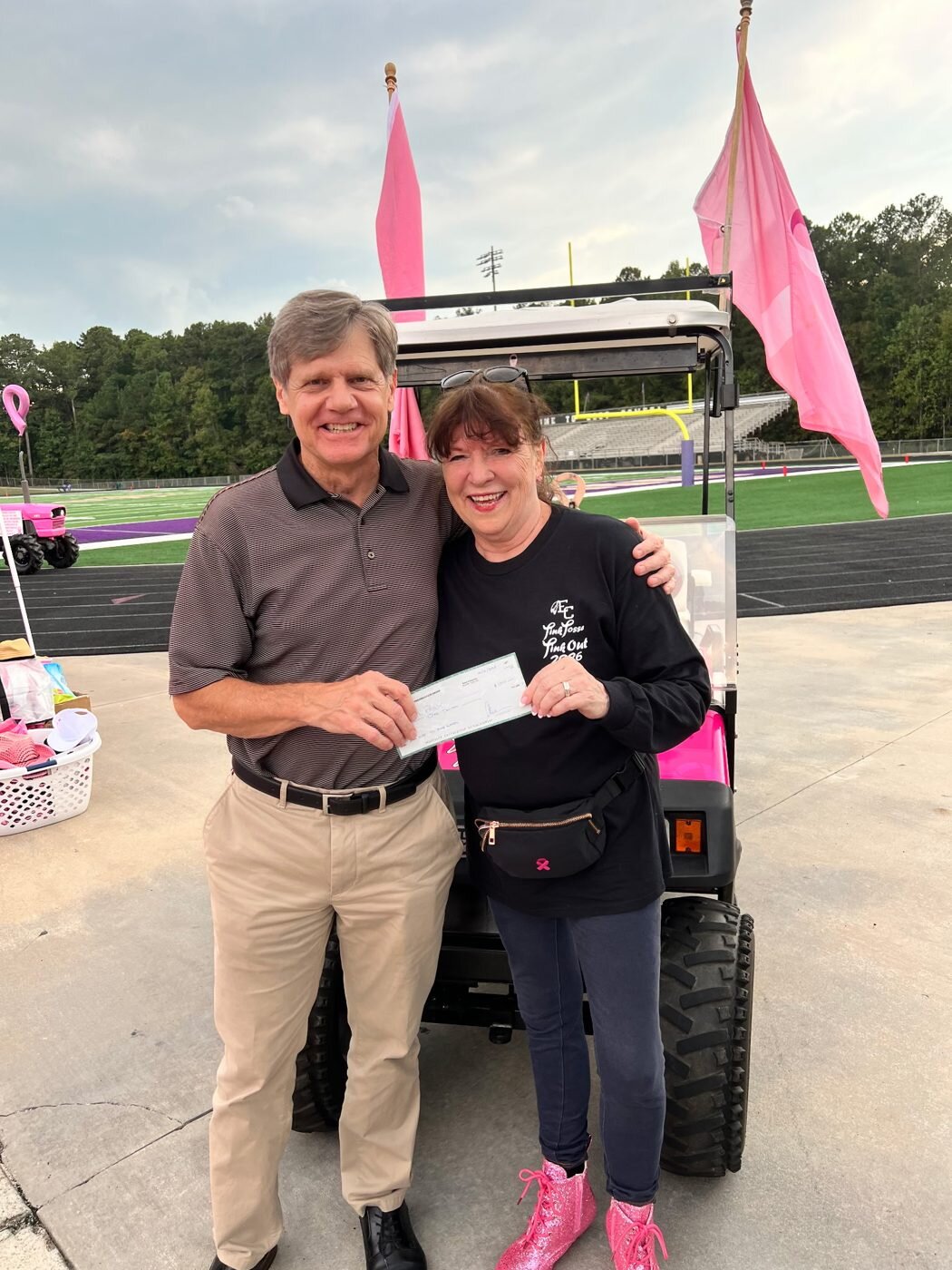 Mark Galvin of CPG and Alice Ramsey hold a donation check for the Pink Posse