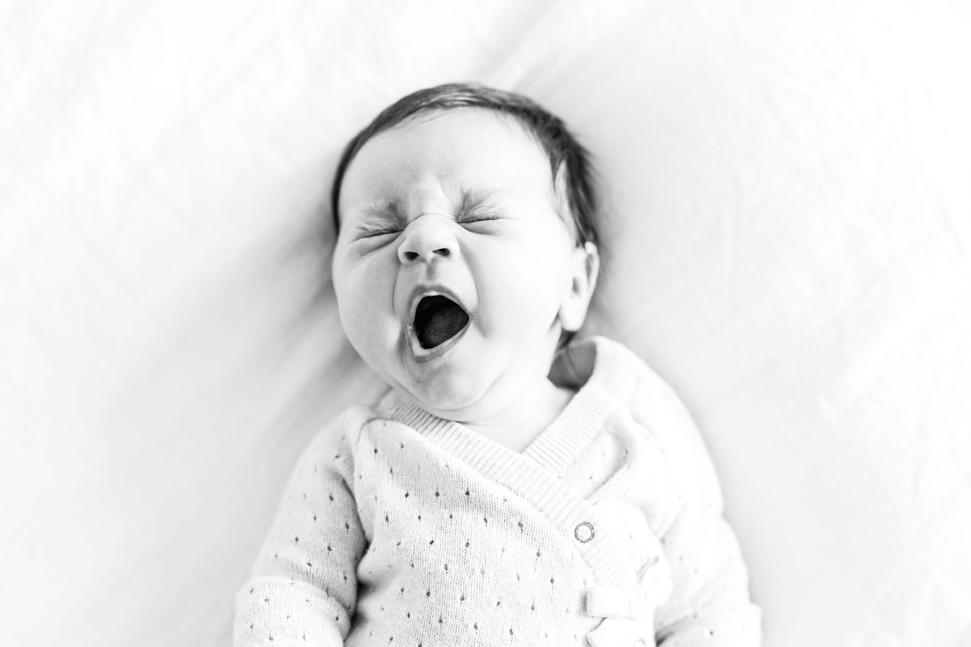Black and white photo of a newborn baby mid-yawn