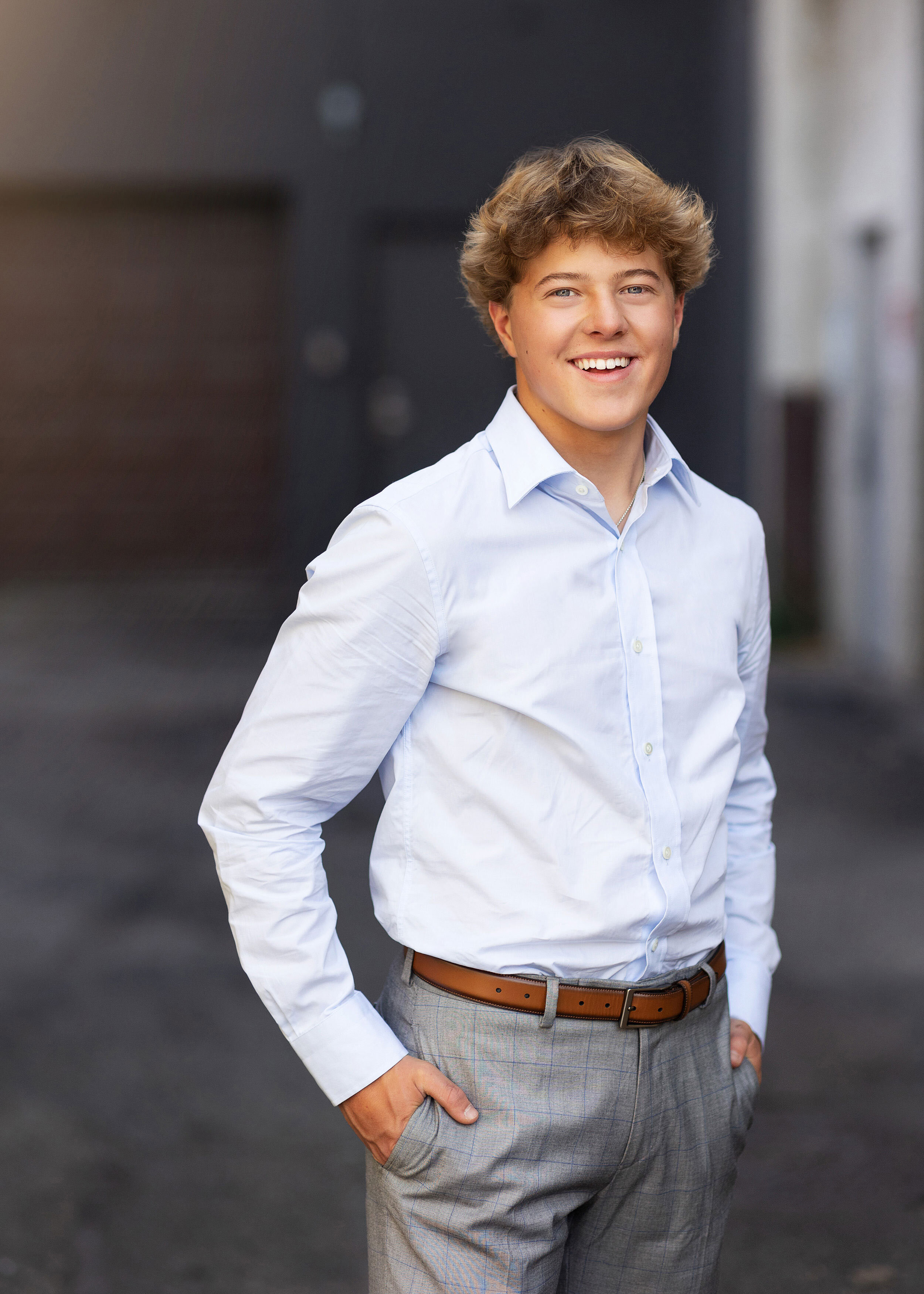 boy wearing dressy clothes stading in downtown Minneapolis alleyway during his senior pictures in minnesota