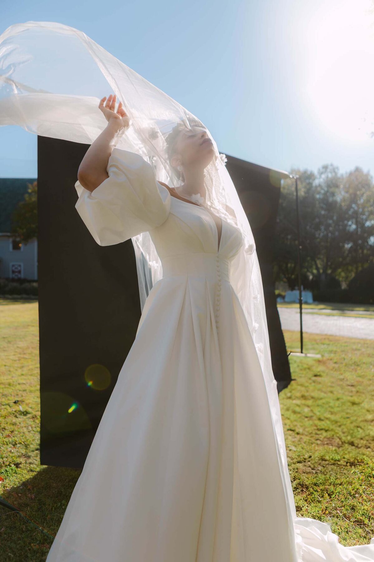 Wedding photography: bride lifting her cathedral veil on a sunny lawn