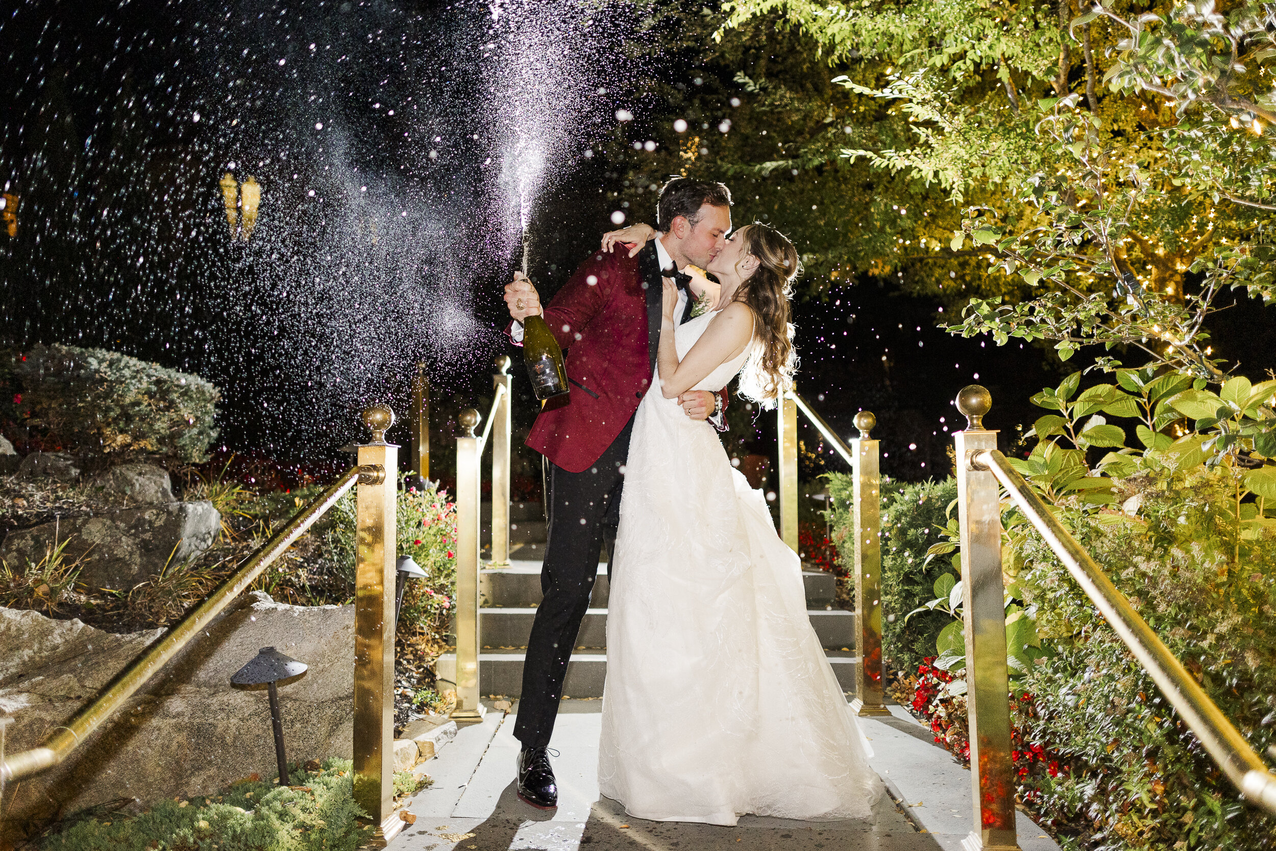 Bride and groom kiss under a champagne spray at their fall wedding at the Abbey Inn and Spa in Peekskill