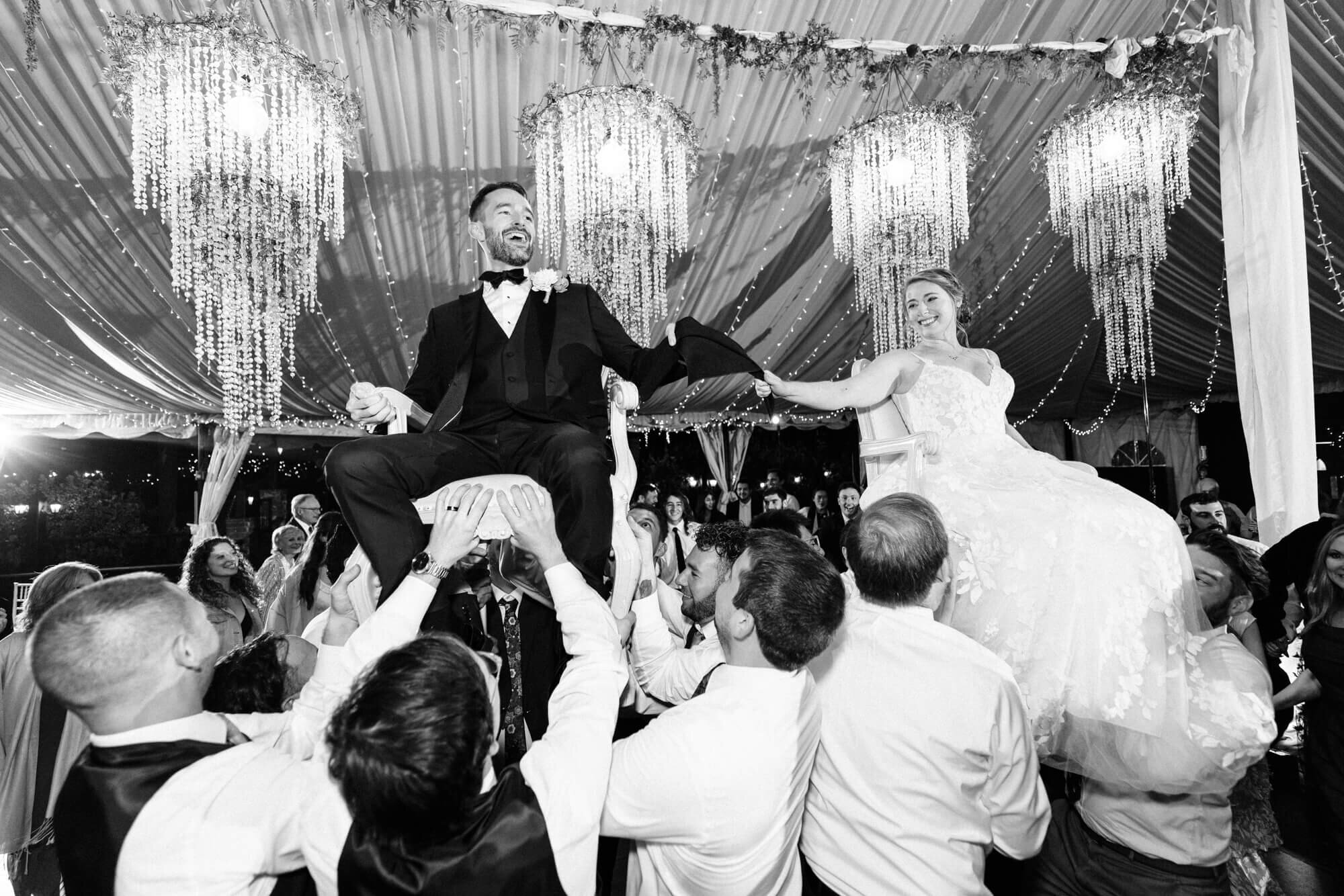 Newlyweds lifted on chairs during their wedding reception