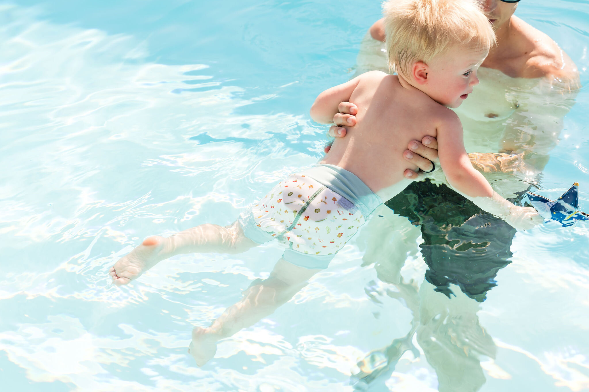 Swim instructor assisting a child poolside for Splash About lifestyle photography
