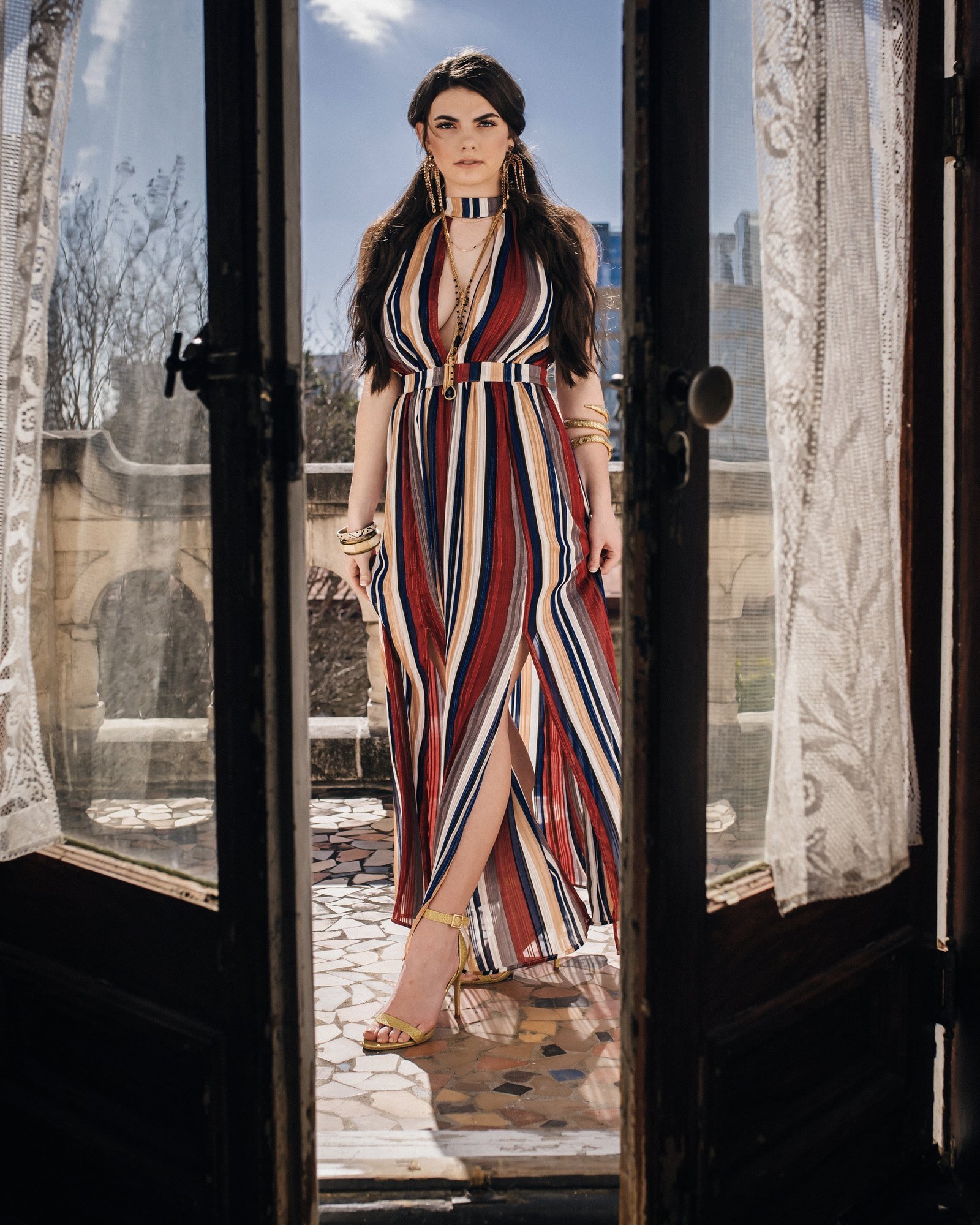 High school senior girl in a striped maxi dress standing in an old doorway, editorial senior portrait by Renee Bowen