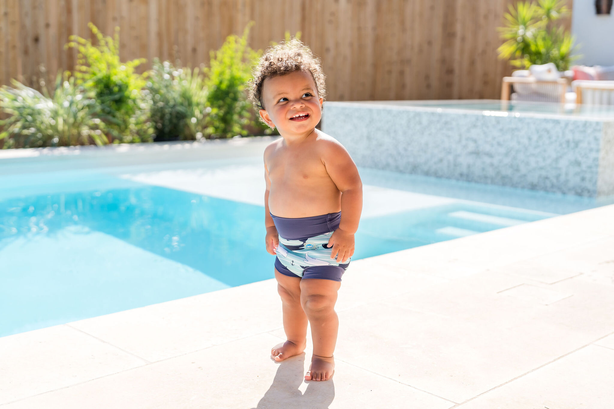 Toddler boy wearing shark print swim trunks for Splash About
