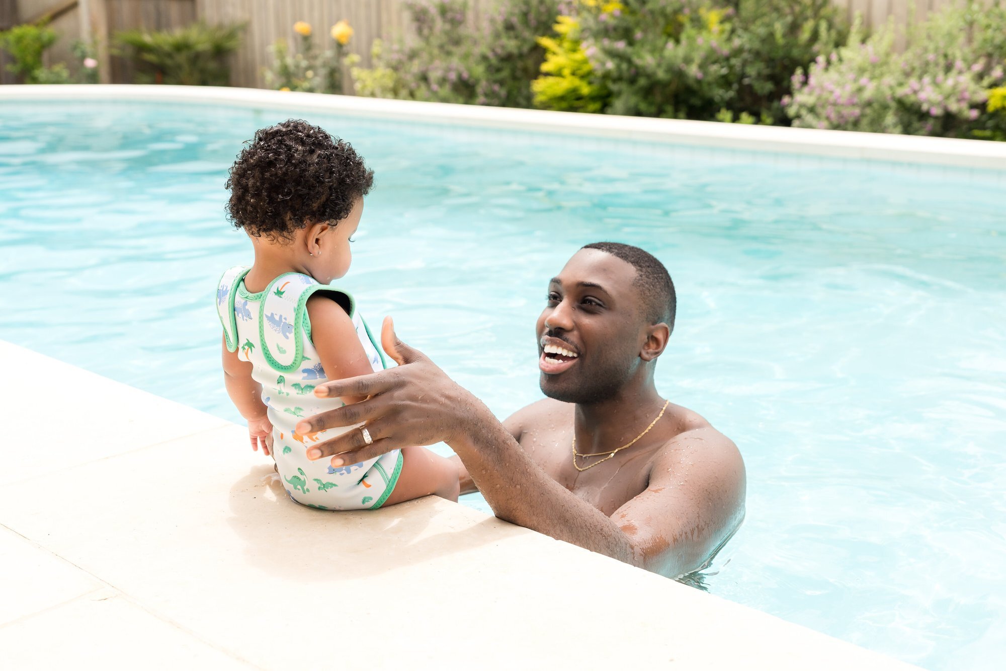 Father and baby laughing at the pool edge wearing Splash About swimwear, Austin