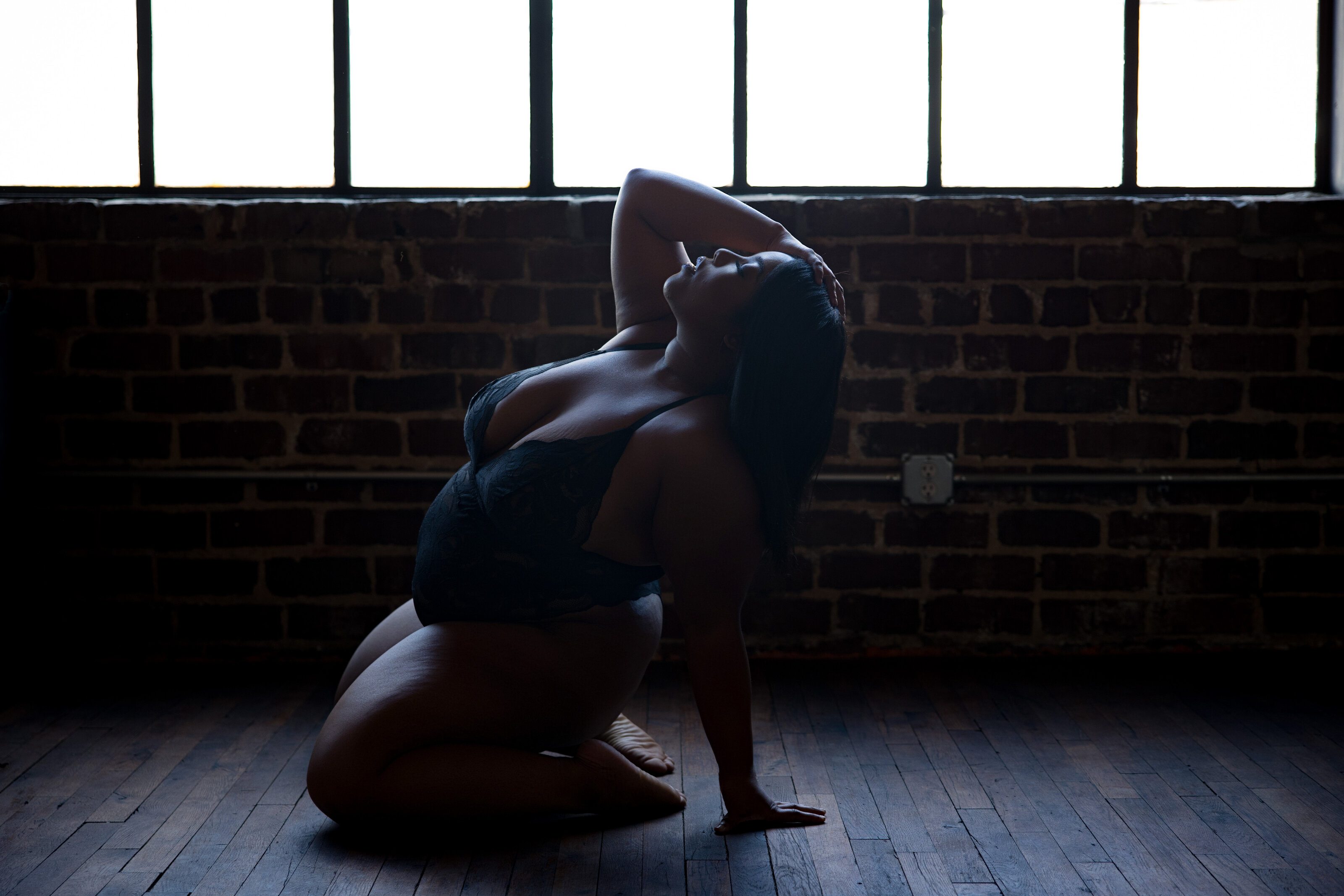 DC boudoir photography — woman leaning back in moody lighting