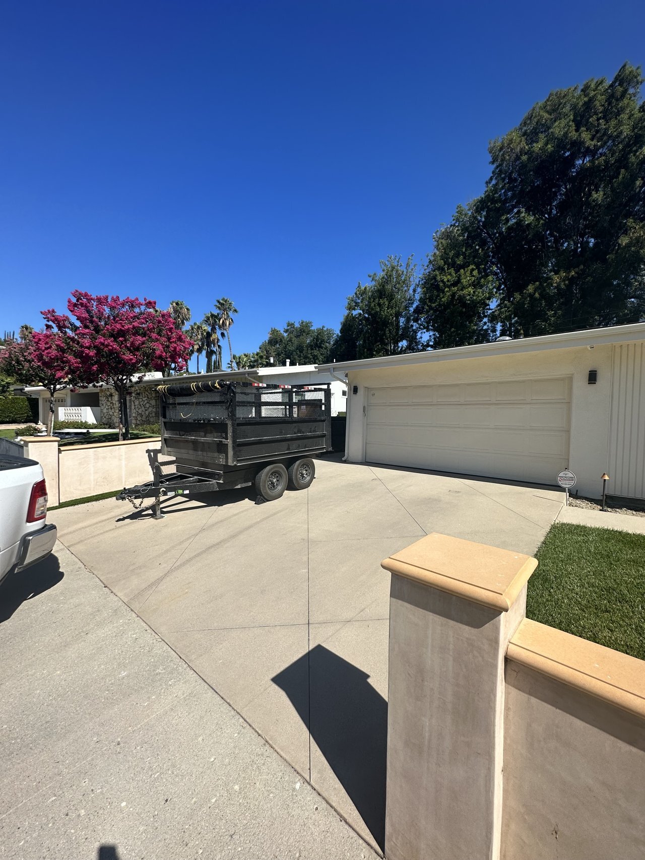 A dumpster trailer placed in front of a residential garage