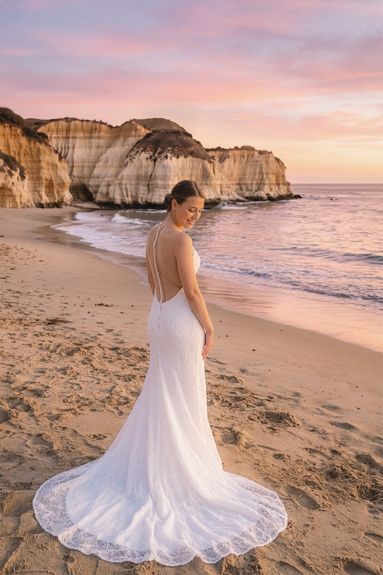 Bride standing on a Malibu beach beneath a pastel golden-hour sky