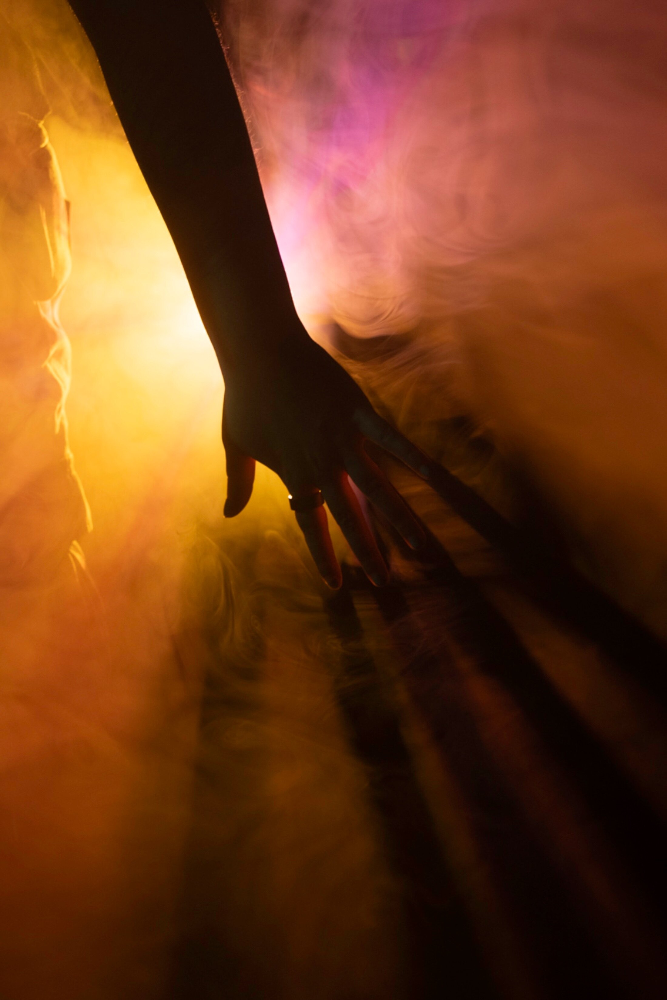 A hand cuts through smoke and orange light.