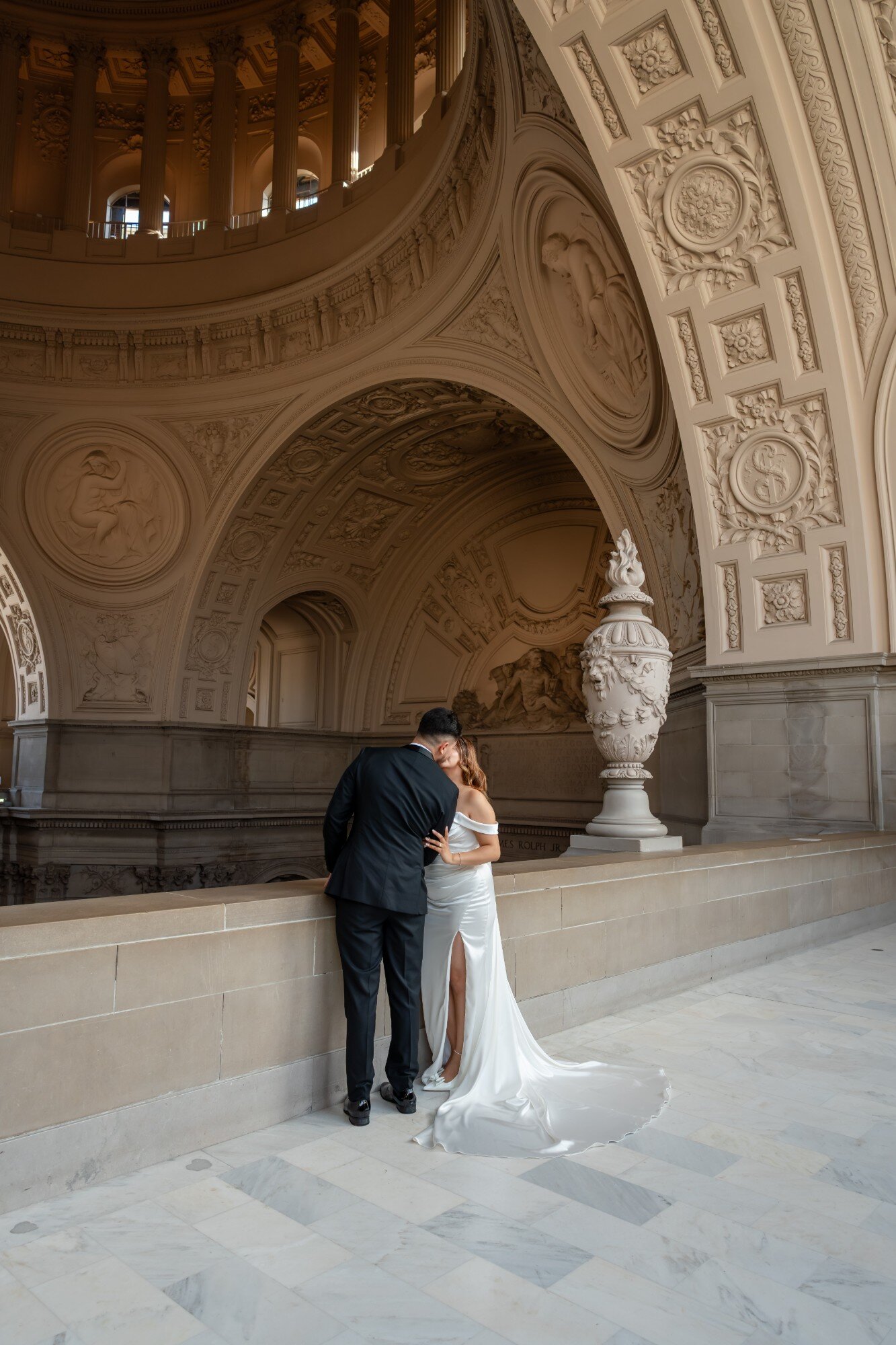 Couple sharing a kiss beneath an arch at SF City Hall
