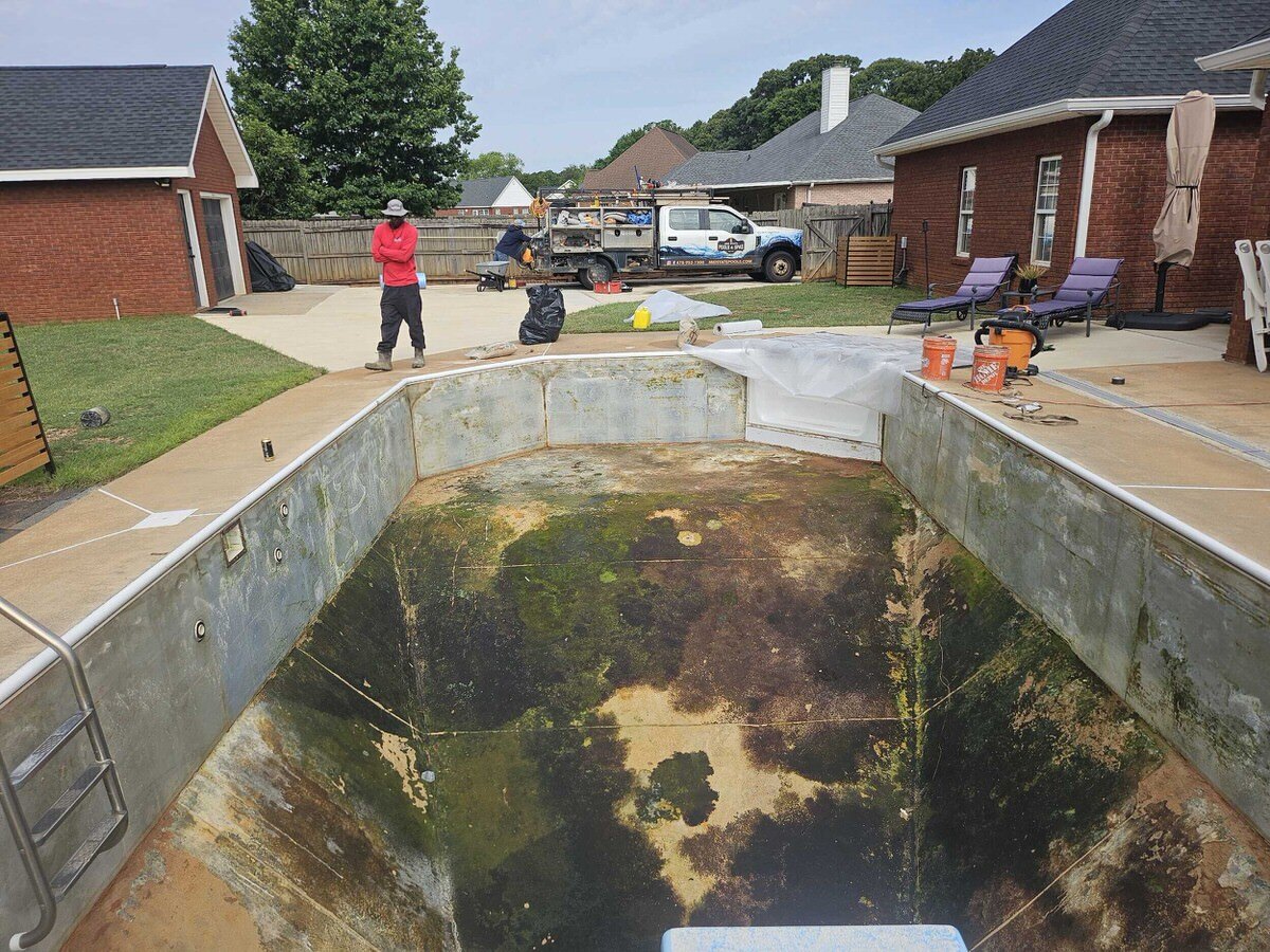 Inground pool before renovation — dated stamped concrete deck and raised stone spa in Middle Georgia