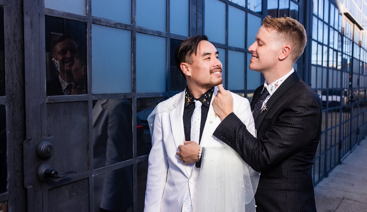 Groom adjusting his partner’s tie before their wedding
