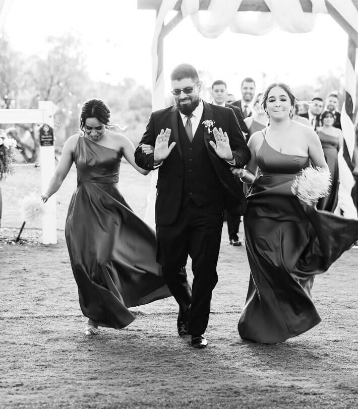 Groom walking with bridesmaids in a black-and-white wedding photo