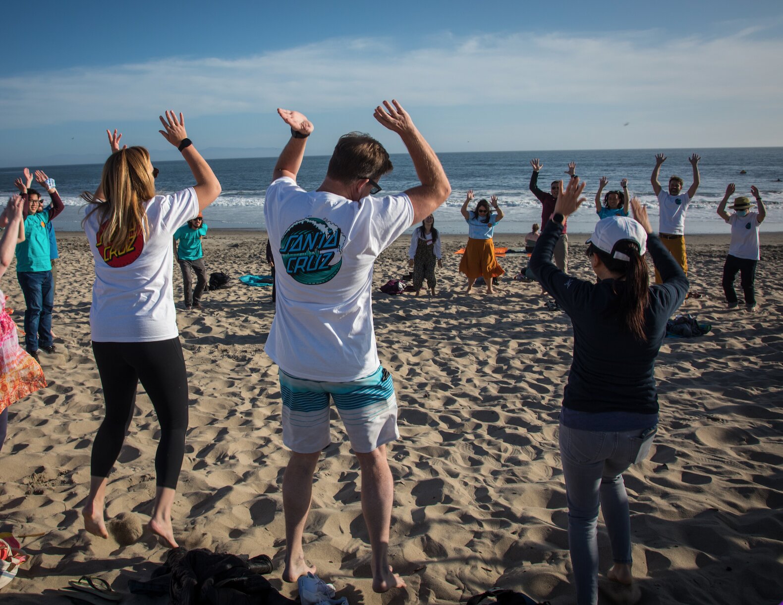Team celebrating together on the beach during an Enliven offsite