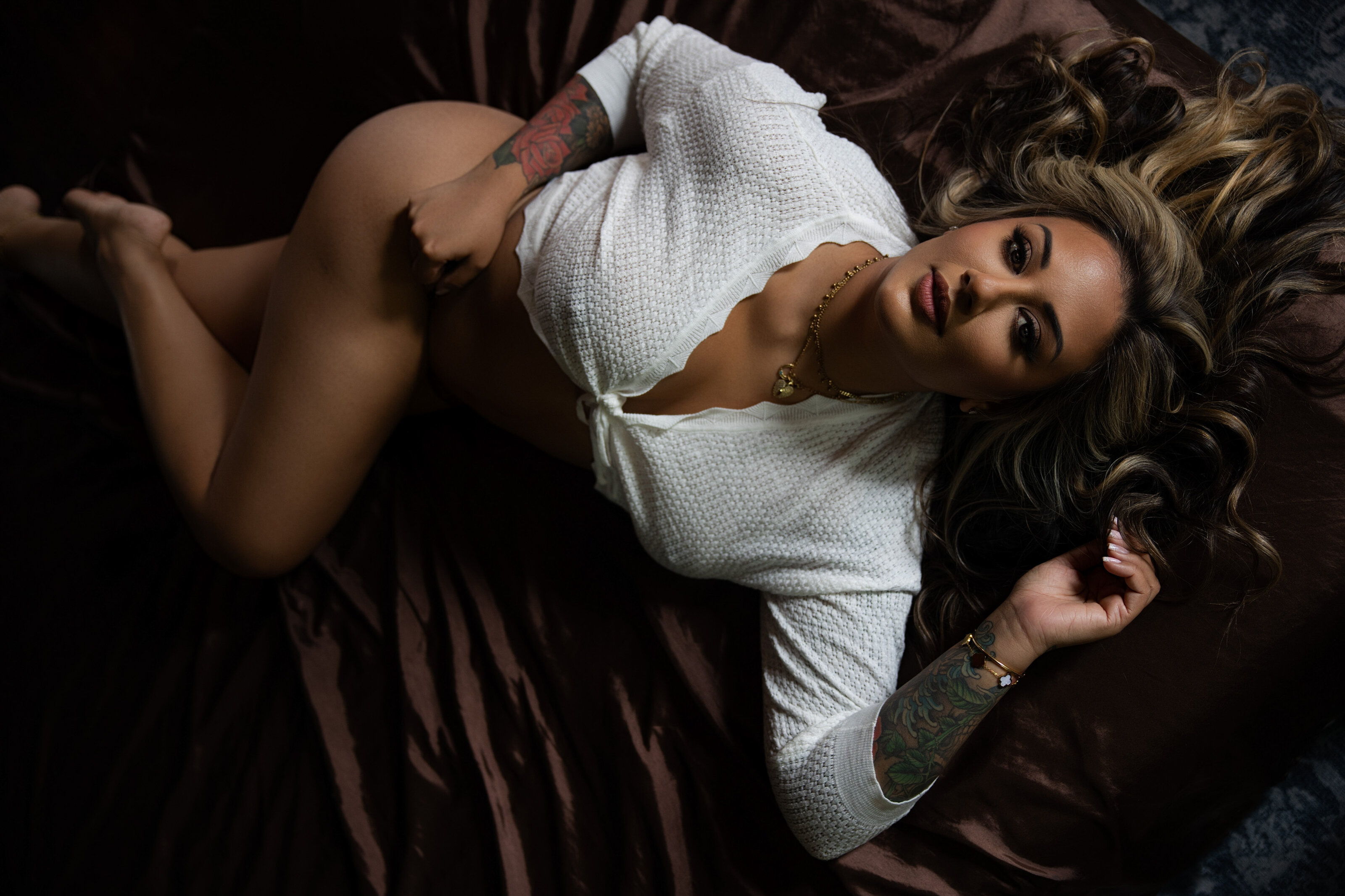A woman in white sweater and lingerie laying on bed during a Baltimore boudoir session by Nicole Griffin Photography