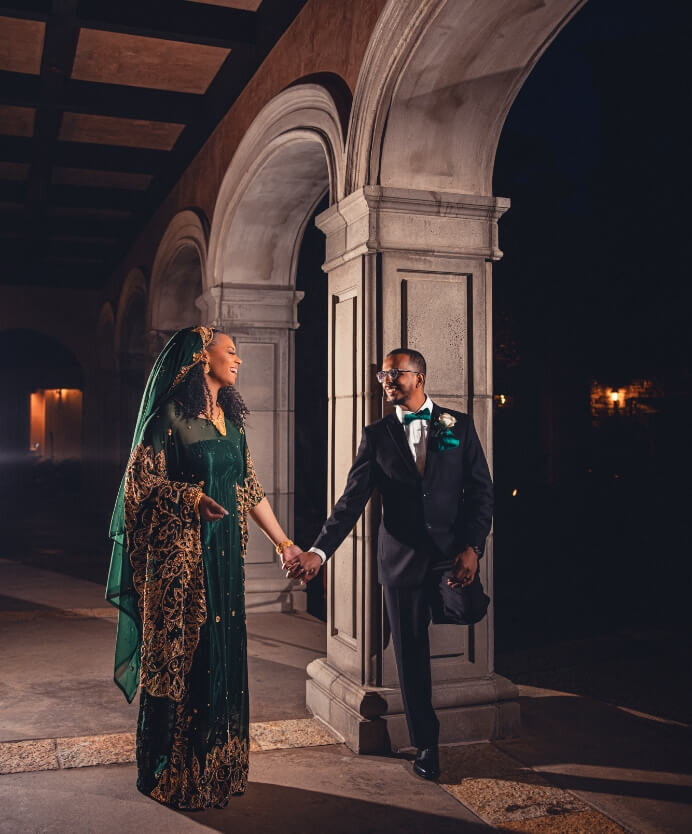 Couple holding hands beneath an elegant arched hallway