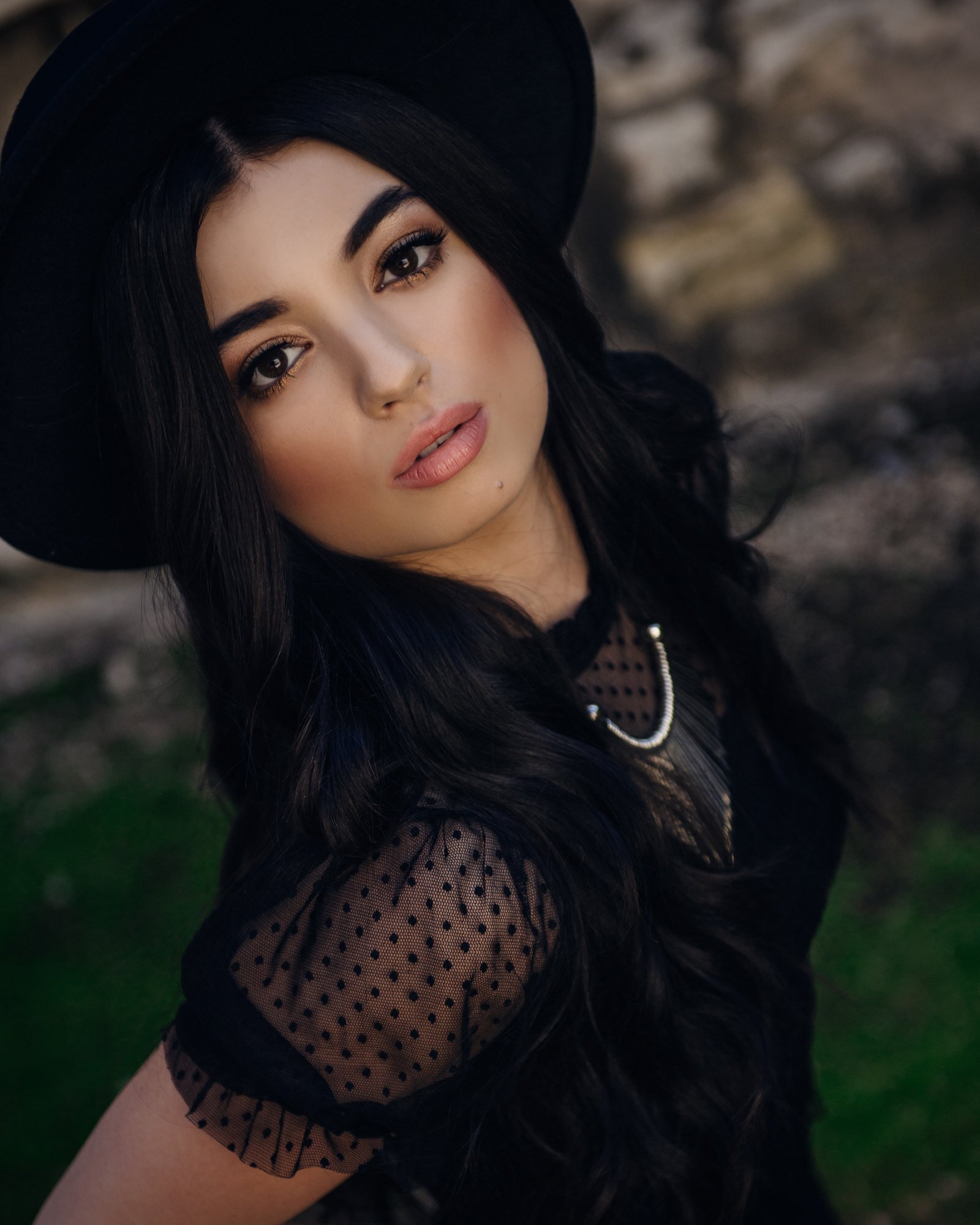 High school senior with dark hair in a black hat and lace top, moody senior portrait by Renee Bowen